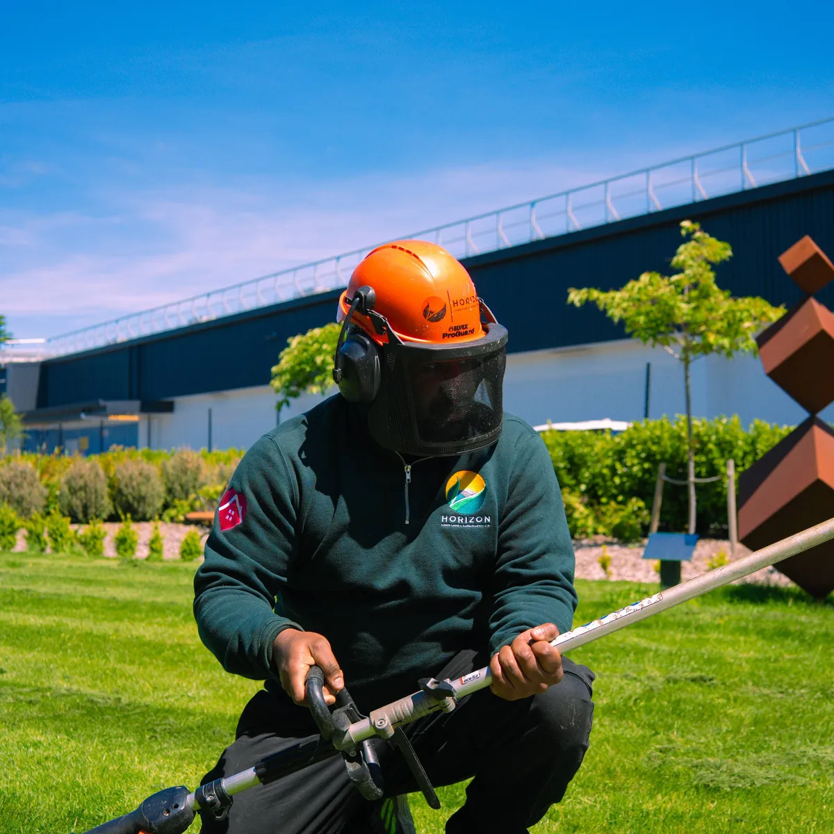Horizon team member trimming a commercial lawn as part of grounds care in Canterbury.